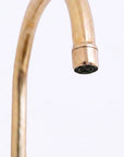 A close-up of a brass faucet spout with a cylindrical head, shown against a plain white background.